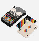 Open box of ‘SMARTLESS’ playing cards featuring images of hosts ‘Jason Bateman,’ ‘Sean Hayes,’ and ‘Will Arnett’ on the box. Two cards are visible — one with a rainbow stripe design and another showing the ‘2 of diamonds’ with the ‘SMARTLESS’ logo printed on the bottom corner.