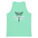 Flat lay of a mint green tank top with artwork that includes a black caduceus symbol—a winged staff with coiled serpents—above bold white text that reads 'STAYING ALIVE', flanked by heartbeat line graphics, and the names 'JON GABRUS' and 'ADAM PALLY' underneath.