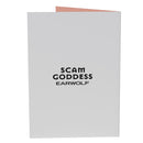 Greeting card featuring a woman with long hair, praying, against a dark background with the text 'Scam Goddess' and an 'Earwolf' logo