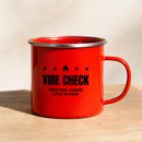 Angled product view of a bright red speckled camp mug with a silver metal rim and red handle, showing the red interior. The black front graphic features four stars surrounding a central flame icon above the text ‘VIBE CHECK’ and ‘HEATED VIBES LIVE SHOW’.