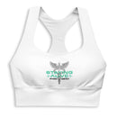 A close-up front view of a white sports bra printed with a green and black ‘STAYING ALIVE’ logo and a caduceus symbol—a winged staff with two snakes—centered on the chest.
