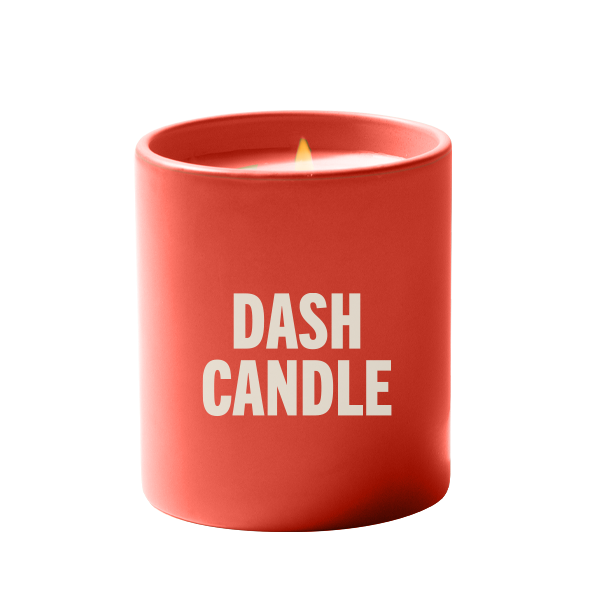 A red candle jar with a small flame, featuring white text on the front that reads ‘DASH CANDLE,’ against a white background.