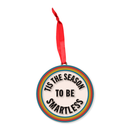 Round ornament with a red ribbon and rainbow border, featuring black text that reads ‘TIS THE SEASON TO BE SMARTLESS.’