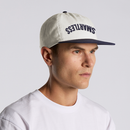 A person wearing a white and navy two-tone baseball cap with the word ‘SMARTLESS’ arched upside down across the front panel.