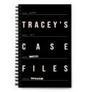 Flat view of a black spiral notebook styled like a case folder. It has white text reading ‘TRACEY’S CASE FILES’ in a stacked layout, with lines indicating a case number, subject, podcast title, and ‘Listen Now: SiriusXM’ at the bottom.