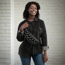 A woman wearing a black denim jacket and jeans smiles while holding a black fanny pack printed with a repeating 'VIBE CHECK' text in white, worn across her chest.