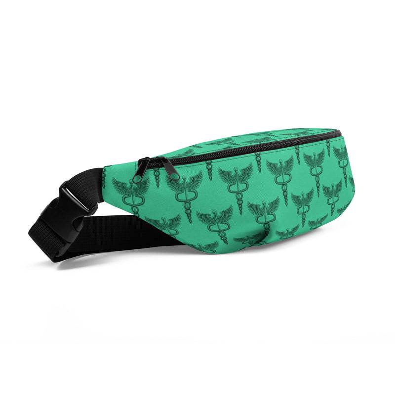 A green fanny pack is shown from a front-left angle with a repeating black print of the caduceus symbol — a staff with two intertwined snakes and a pair of wings at the top, representing medicine and healing. The bag has a black zipper, an adjustable black strap, and a plastic buckle.