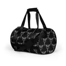A side view of a black gym bag decorated with a repeated pattern of silver caduceus symbols—a winged staff coiled with two snakes—across the fabric. The bag has black handles and an adjustable black shoulder strap with a padded section.