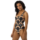 A woman standing and smiling slightly, wearing a black one-piece swimsuit with an all-over 'BYEEEEEEE' rainbow print and a small white 'SiriusXM' logo on the hip area.