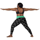 A person in a yoga pose wearing black leggings with a green waistband, printed with a repeating pattern of white caduceus symbols — winged staffs with two snakes — representing medicine.