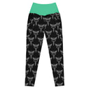 A flat lay of black leggings featuring a green waistband and a white all-over print of caduceus symbols, which are winged staffs with two snakes.