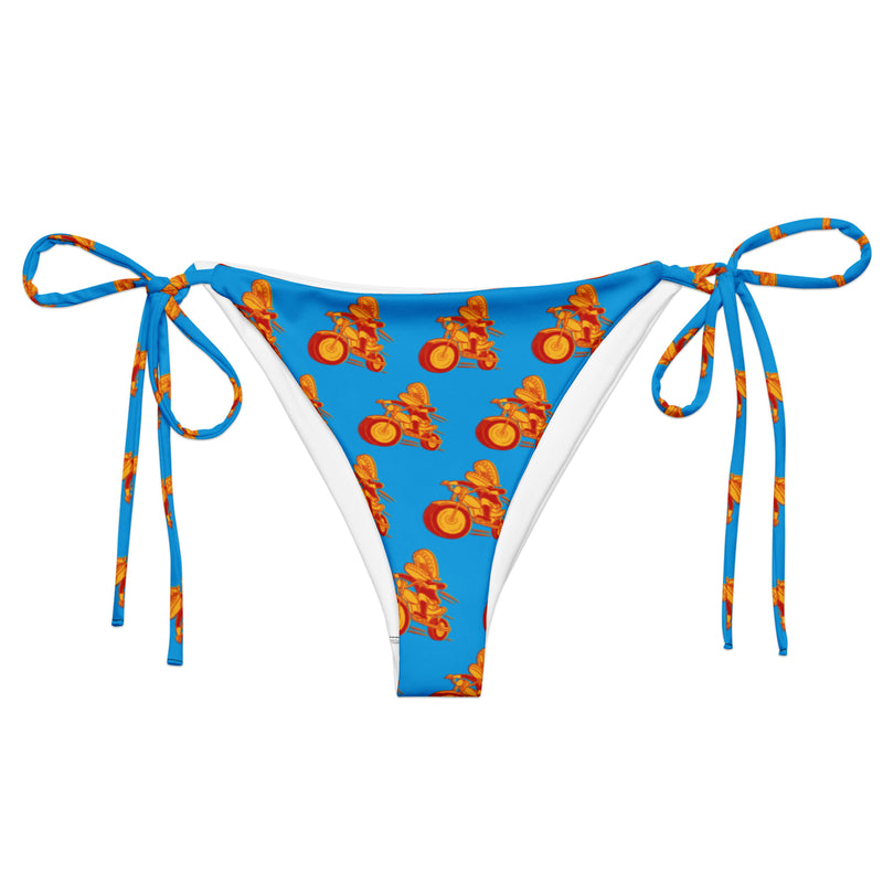 A blue string bikini bottom with adjustable side ties, featuring a repeating printed pattern of the red and yellow Motormouth character riding a motorcycle.