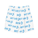 Back view of white swim trunks with elastic waistband and all-over repeating light blue ‘WET DAY’ text and splash graphics. The pattern continues across the entire garment, showing consistent print coverage.