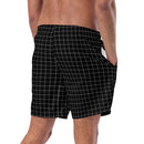 A man is shown from the waist down wearing black swim trunks with a white grid pattern. His right hand is in the side pocket, and the mesh lining is partially visible.