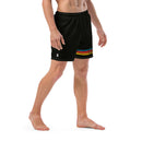 A man stands barefoot wearing black mid-length swim trunks featuring a small white 'SiriusXM' logo on the left leg and horizontal stripes in blue, red, orange, and yellow near the hem, with the text 'SEXY INDIFFERENCE' repeated across the colored bands.