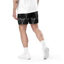 A person walking away in black mesh shorts covered in repeating caduceus symbols—a winged rod with two snakes, associated with medicine. Paired with white sneakers and socks.