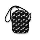 A black utility crossbody bag laid flat against a white background, featuring an all-over diagonal print of the phrase 'VIBE CHECK' in bold white text and an adjustable black strap.