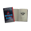 Product image of the signed novel ‘THE BUTCHER GAME’ by ‘ALAINA URQUHART’. The front cover shows a red maple leaf with dripping blood and the title ‘THE BUTCHER GAME’. Beside it, the book is open to a title page reading ‘THE BUTCHER GAME’ with an author signature below.