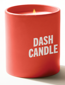 A red candle jar with a lit flame and white text on the front that reads ‘DASH CANDLE.’