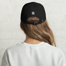 Woman facing away, wearing a black dad hat with an adjustable strap and metal clasp. The back features a white embroidered 'S' logo centered above the opening.