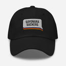 Black dad hat with a white embroidered speech bubble patch on the front. Inside the patch, bold black text reads 'SAYONARA SUCKERS' above horizontal embroidered stripes in red, orange, blue, and yellow.