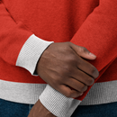 Close-up of hands wearing a red sweater with gray ribbed cuffs and hems.