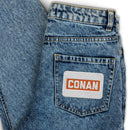 Denim jeans with a label reading 'CONAN' on the back pocket.