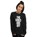 A woman wearing a black long sleeve shirt with large white vertical text that reads 'THE VIBES ARE OFF' on the front.
