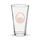 Clear glass pint glass with an orange circle logo featuring a stylized white design of a head with hair