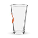 Clear glass pint glass with an orange circle logo featuring a stylized white design of a head with hair
