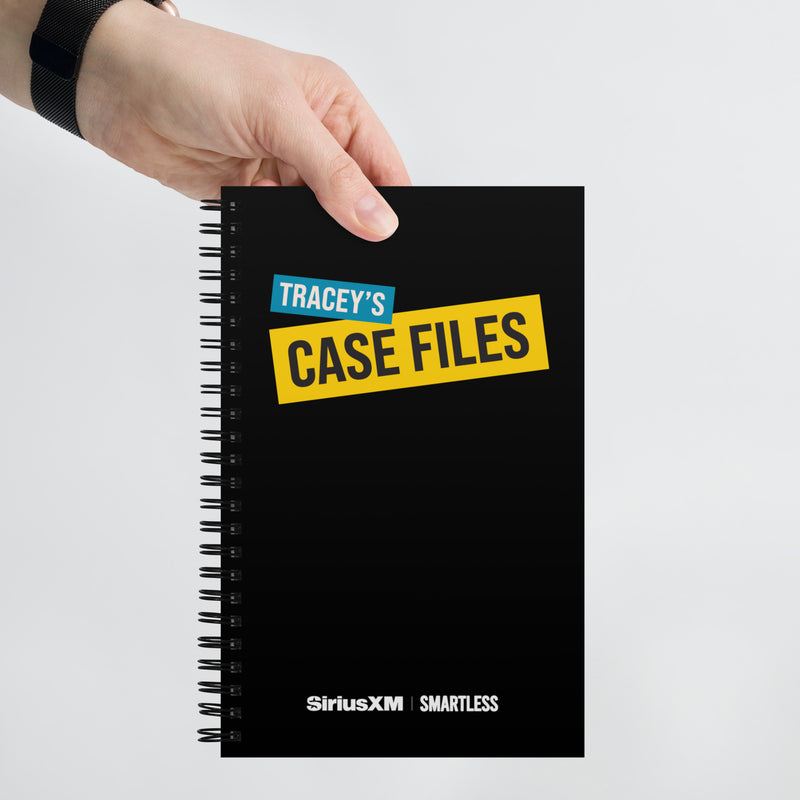 A hand holds up the black spiral notebook against a white background. The front cover displays 'TRACEY'S CASE FILES' in cyan and yellow block lettering, with 'SiriusXM' and 'SmartLess' logos along the bottom edge.