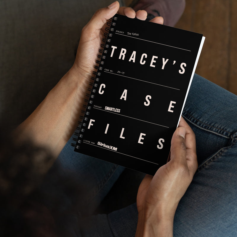 Person sitting and holding the black spiral notebook in their lap. The cover is styled like an evidence file with the title ‘TRACEY’S CASE FILES’, including details like case number, subject, and 'SiriusXM' and 'SmartLess' logos.