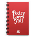 A red spiral-bound notebook with the phrase 'Poetry Loves You' in large white retro-style text centered on the cover. The words 'VIBE CHECK' appear in smaller white capital letters at the bottom.