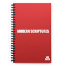 A red spiral-bound notebook with the phrase 'MODERN SCRIPTURES' in bold white capital letters centered on the cover. The 'VIBE CHECK' logo appears in small white text at the bottom right.