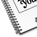 A close-up angled view of the white spiral notebook showing the black wire binding, a portion of the text 'Poetry Loves You', and the smaller 'VIBE CHECK' text at the bottom right.