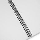 Close-up of the inside of the spiral notebook, showing white dotted grid pages and the black metal coil binding.