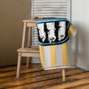 Folded towel draped over a wooden chair in a home setting, with the sardine can design partially visible and yellow and white stripes.
