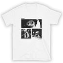 Front view of a white short-sleeve T-shirt with a centered rectangular black-and-white collage graphic. The design includes a close-up eye with silhouetted hands in the pupil, a hooded figure standing in a forest, and a skull resting on books beside a lit candle. The text ‘MORBID’ appears above the collage, and ‘KEEP IT WEIRD’ is printed below the lower right panel.