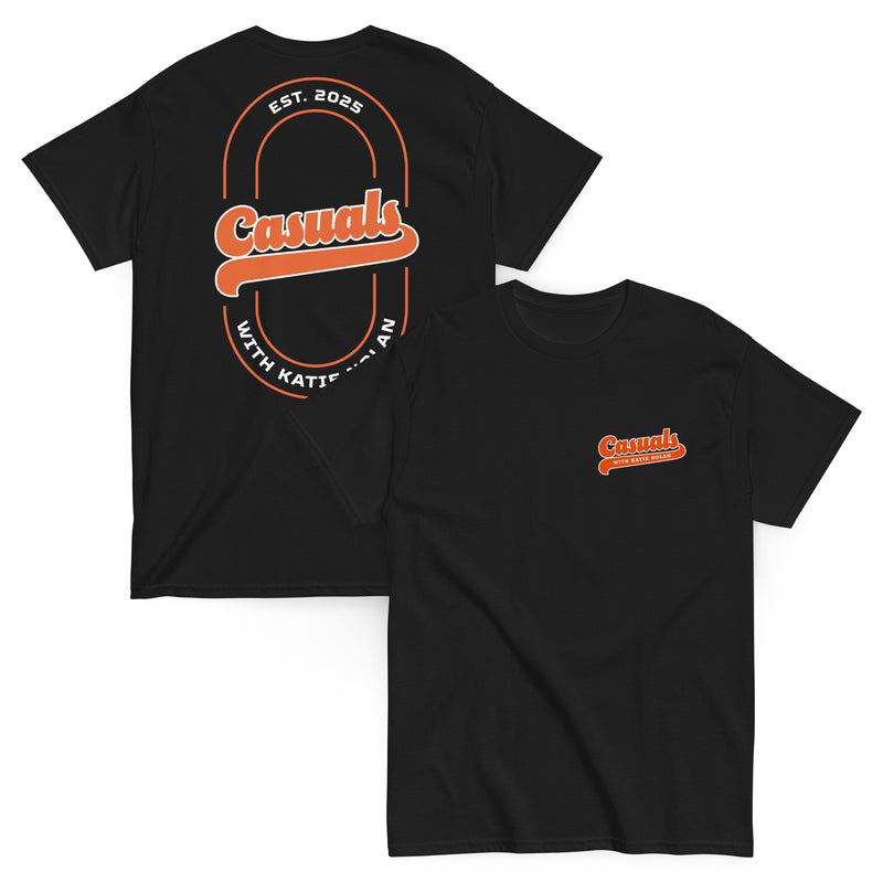 Two black short-sleeve T-shirts laid flat, front and back view. The front shirt shows a small orange and white 'Casuals WITH KATIE NOLAN' logo on the left chest, and the back shirt features a large oval graphic with 'Casuals,' 'EST. 2025,' and 'WITH KATIE NOLAN.'