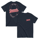 Two navy blue short-sleeve T-shirts laid flat, front and back view. The front shirt shows a small red and white logo on the left chest reading 'Casuals WITH KATIE NOLAN,' while the back shirt displays a large oval graphic with 'Casuals,' 'EST. 2025,' and 'WITH KATIE NOLAN.'