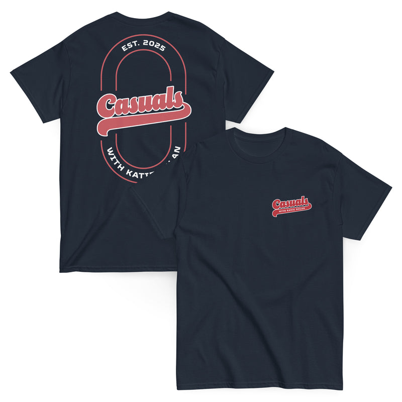 Two navy blue short-sleeve T-shirts laid flat, front and back view. The front shirt shows a small red and white logo on the left chest reading 'Casuals WITH KATIE NOLAN,' while the back shirt displays a large oval graphic with 'Casuals,' 'EST. 2025,' and 'WITH KATIE NOLAN.'