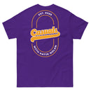Purple short-sleeve t-shirt laid flat, showing the back design: a large gold and white oval outline with 'Casuals' in bold gold letters, 'EST. 2025' above in white, and 'WITH KATIE NOLAN' curved below in white.