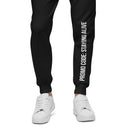 Front view of black sweatpants with white text on the left leg that reads 'PROMO CODE: STAYING ALIVE'. The pants are paired with white sneakers.