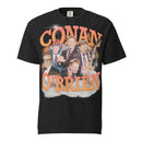 A black t-shirt featuring a graphic design of Conan O'Brien with multiple images of him in different expressions and outfits, including one with glasses and another playing a guitar. The text 'CONAN O'BRIEN' is prominently displayed in bold, orange 3D letters with a cloud-like and lightning background.