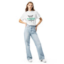 Woman wearing a white graphic T-shirt with a large caduceus (a winged staff with two snakes), mint green 'STAYING ALIVE' lettering, and black text below that reads 'Jon Gabrus' and 'Adam Pally', styled with light blue high-waisted jeans.