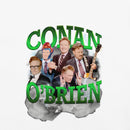 Close-up of white T-shirt graphic showing the vivid green 3D lettering ‘CONAN O’BRIEN’ arched across the design. The collage includes five images of Conan O’Brien layered over smoky gray clouds with white lightning streaks. One version wears a bright red and blue helmet, another plays a guitar with a strap reading ‘CONAN’, while others wear suits and make expressive gestures.