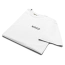 White heavyweight T-shirt shown folded at an angle, highlighting the upper chest area. The word ‘MORBID’ is printed in small black serif-style capital letters on the left chest. The fabric appears thick and soft with subtle folds along the sleeves and collar.