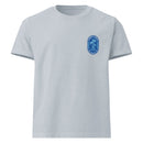 A light blue oversized t-shirt laid flat, displaying a small blue oval logo on the left chest that reads ‘Summer S’mores with Conan & the Chill Chums, Los Angeles, CA’ with palm trees and a checkered border.