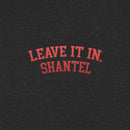 A close-up view of a black heather fabric showing red arched text printed on it. The text reads 'LEAVE IT IN, SHANTEL' in bold, all-caps lettering.