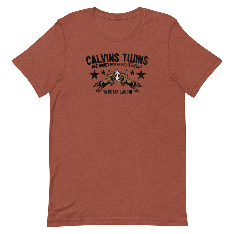 Heather clay short-sleeve t-shirt with black text 'CALVINS TWINS' above an illustration of two horses colliding headfirst, surrounded by black stars. Smaller text reads 'BEE HONEY HORSE FIGHT FIELDS' above and 'YA GOTTA LAUGH!' below.